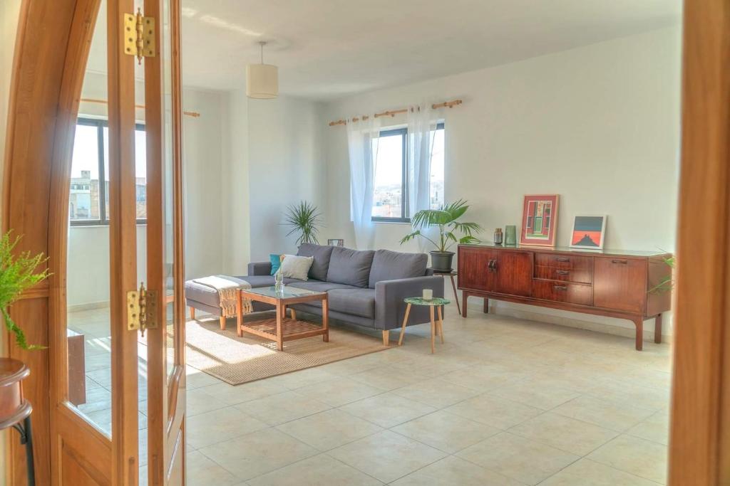 uma sala de estar com um sofá e uma mesa em Double bedroom with ensuite in spacious corner apartment em Birkirkara