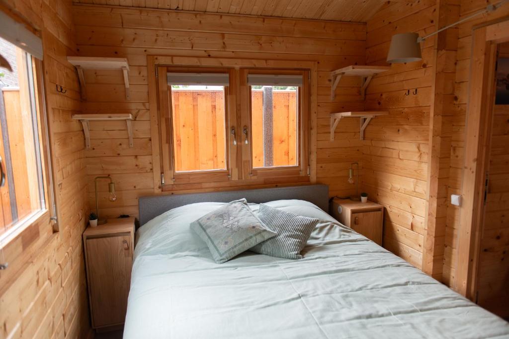 Cama en habitación de madera con 2 ventanas en Logeren in Veere en Veere