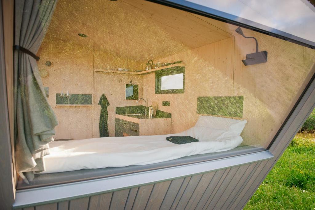 ventana de cristal de un dormitorio con cama y lavabo en Friesland Glamping Camp Schortens, en Schortens