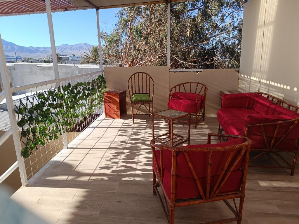 een patio met stoelen en een bank op een veranda bij Hostal Ollague, habitaciones con baño privado in Calama