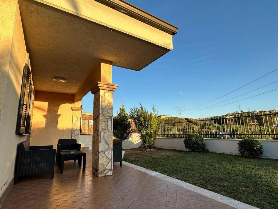 eine überdachte Terrasse mit einem Tisch, Stühlen und einem Zaun in der Unterkunft Casa Ninetta Marco Simone in Marco Simone