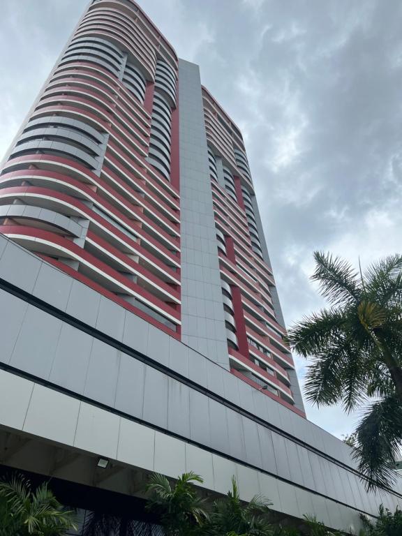 un edificio alto rojo y blanco con una palmera en Flat Boulevard Side 2104 Altissimo Padrão com Lazer en Salvador