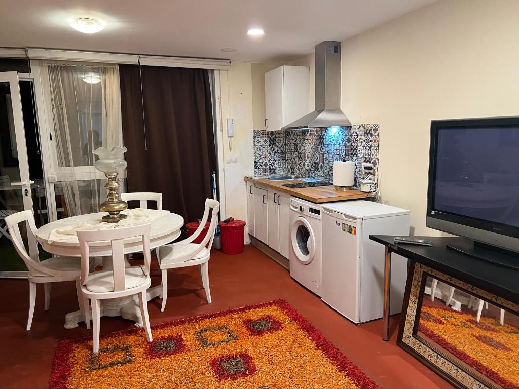 een woonkamer met een tafel en een keuken met een tv bij Apartamento abierto con patio in Matadepera