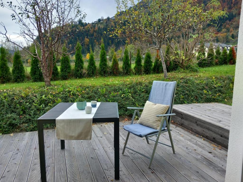 a table and a chair on a wooden deck at Feriennest Ossiachersee in Bodensdorf