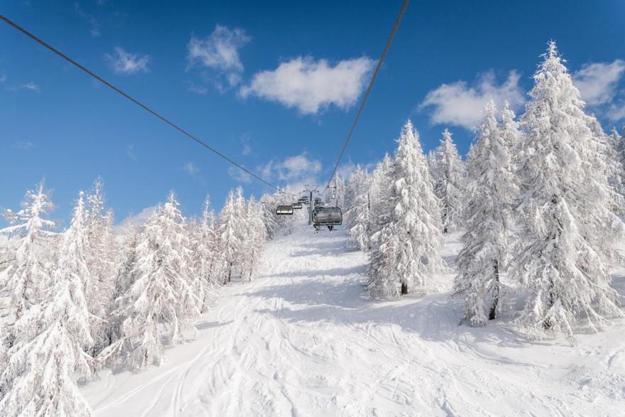 a ski lift with snow covered trees on a ski slope at Feriennest Ossiachersee in Bodensdorf