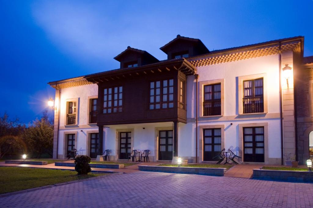 un gran edificio blanco con ventanas negras por la noche en La Casona de la Roza, en Valbucar