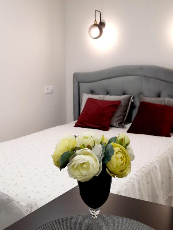 eine Vase mit gelben Blumen auf einem Tisch neben einem Bett in der Unterkunft P Komunos Apartamentai Netoli Akropolio in Klaipėda