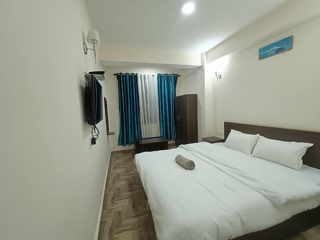 a bedroom with a large white bed and a television at Snow Drop Guest House in Gangtok