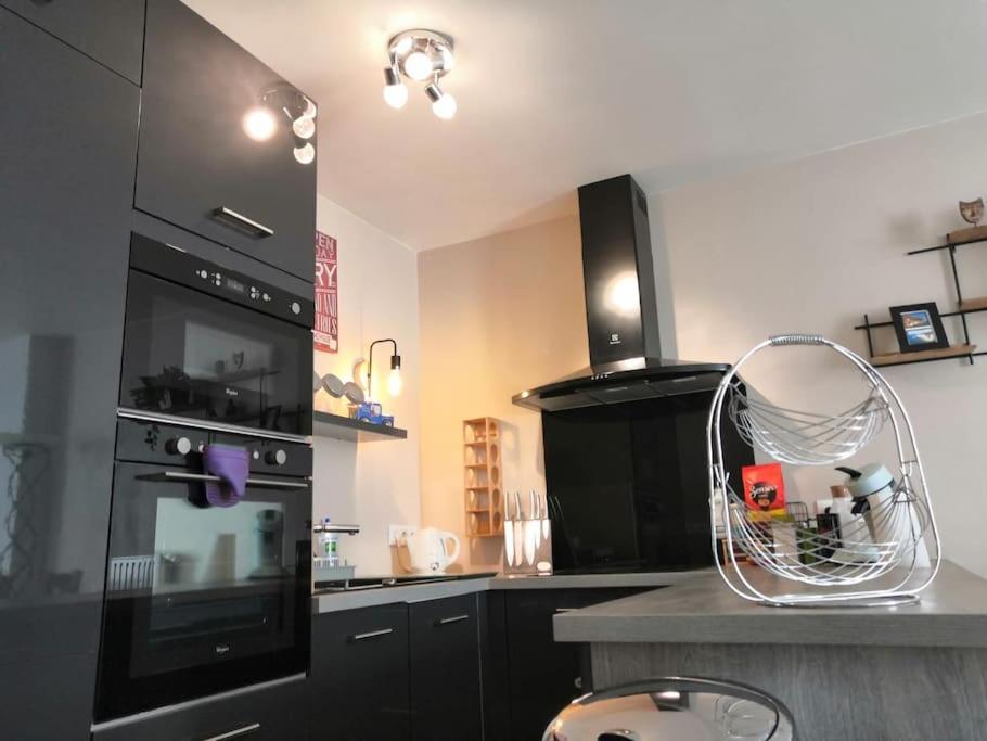 eine Küche mit schwarzen Schränken und einem schwarzen Backofen in der Unterkunft Joli T2 - 4P Bien équipé - Palaiseau Massy Orly in Palaiseau