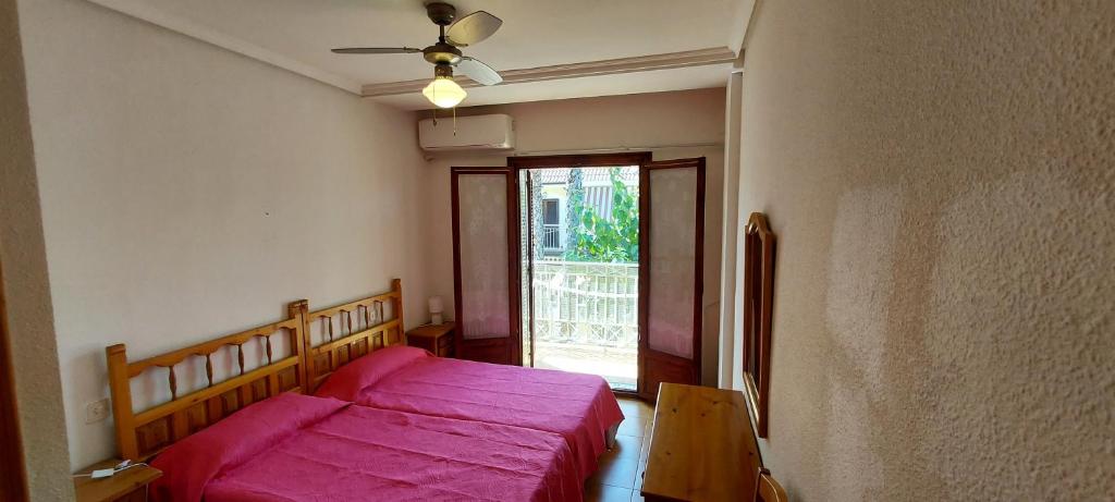a bedroom with a pink bed and a window at Bungalow Iratxe en Santa Pola in Santa Pola