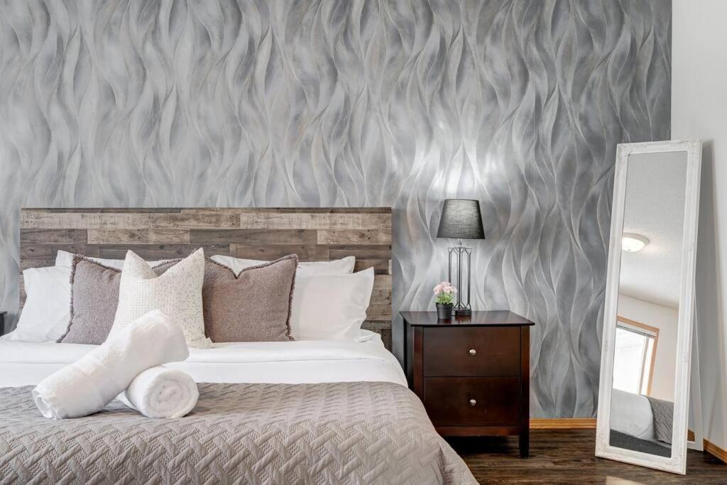 a bedroom with a large bed and a mirror at Coral Springs Lakefront Retreat in Calgary