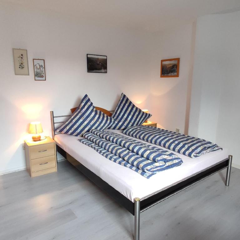 a bed with blue and white pillows and a night stand at Gästehaus Familie Rinke in Bad Harzburg