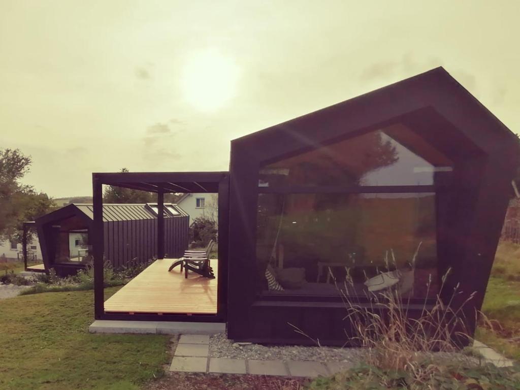 ein Haus mit einer großen Glastür und einer Terrasse in der Unterkunft Tiny House 1 im schönen Allgäu mit großem Garten, Naturnah in Bad Wurzach