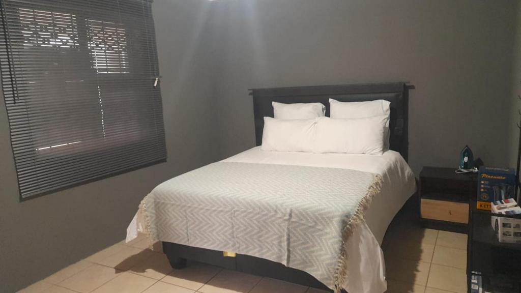 Schlafzimmer mit einem Bett mit weißer Bettwäsche und Kissen in der Unterkunft Garden Street Apartments in Alice