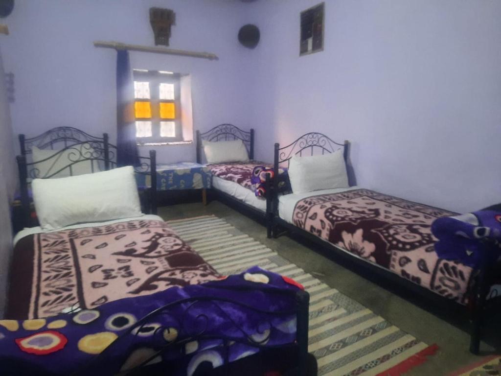 een kamer met 3 bedden en een raam bij Gite d'étape chez zaid ouchaoua famille in Imilchil