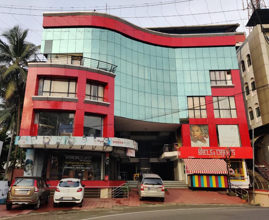 un edificio rojo con coches estacionados frente a él en Amruth Inn, en Guruvāyūr