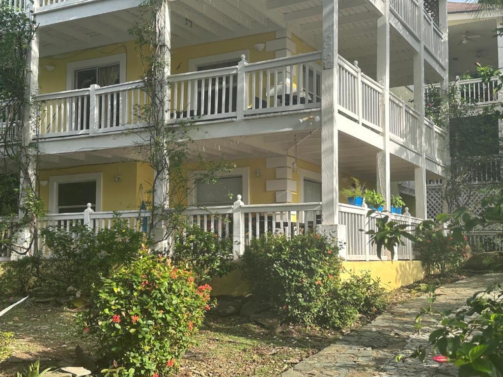 a yellow house with a white balcony and bushes at Villa Rehobot in Contadora