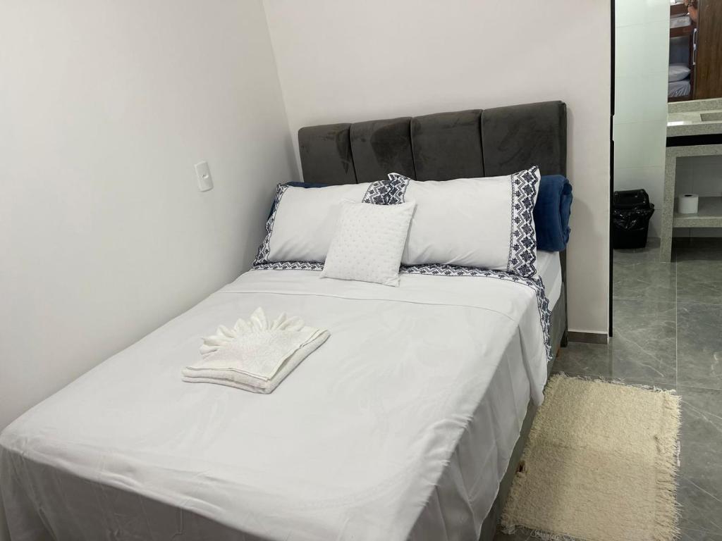 uma cama com lençóis brancos e almofadas num quarto em Pousada Jeová Jireh em Penha