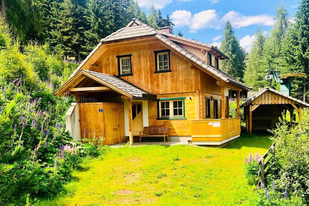 een klein houten huis met een tuin ervoor bij Ferienhaus Kärnten Stückler in Hochrindl