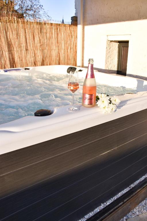 a bottle of wine and a glass on a table at Maison au calme avec jacuzzi privatif in Cambrai