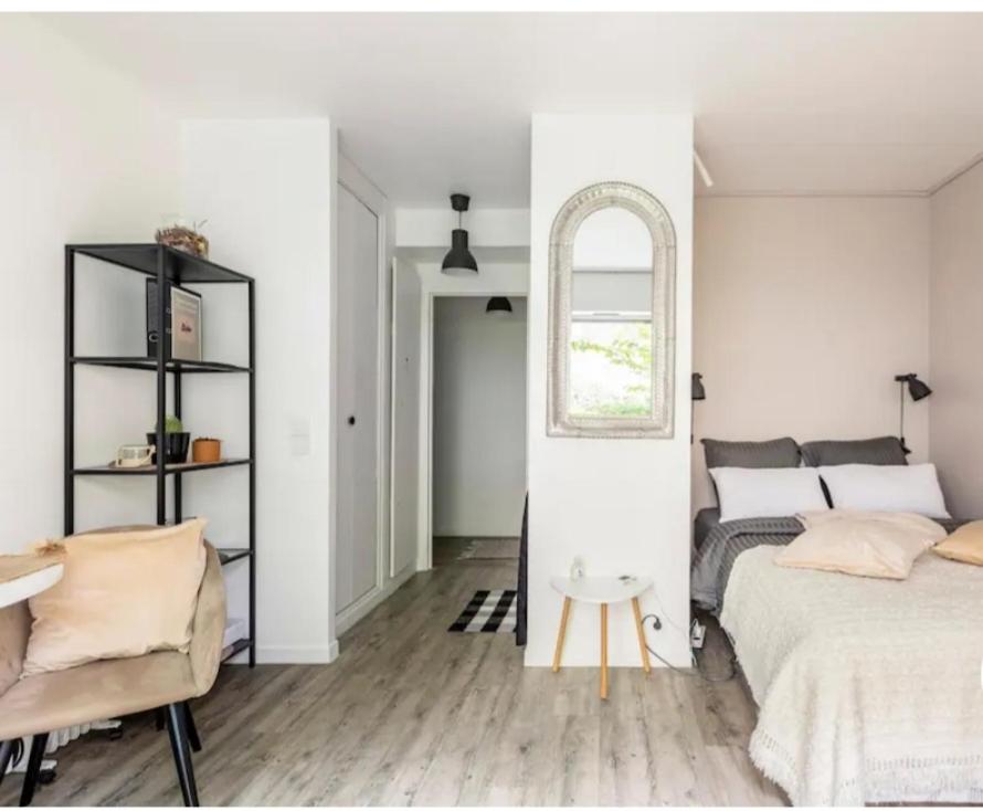 una camera bianca con un letto e una sedia di Appartement Cosy Paris centre a Parigi