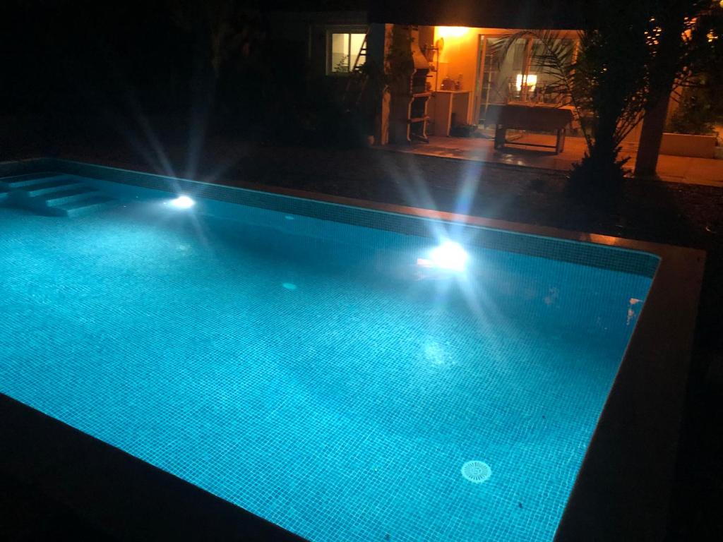 uma piscina à noite com luzes acesas em Casa Papoula em São Brás de Alportel