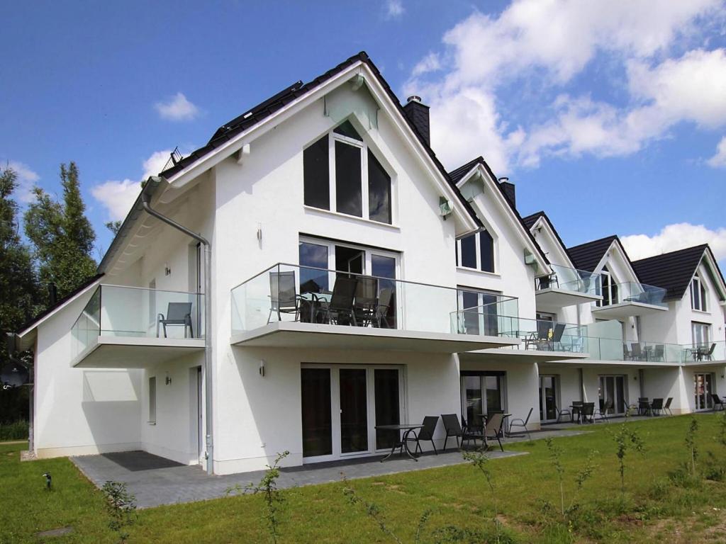 a large white house with chairs on a lawn at Appartement Hafenflair am Plauer See in Plau am See