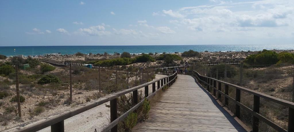 een houten promenade over een strand met de oceaan bij Adosado con piscina y terraza a 700m de la playa in Gran Alacant