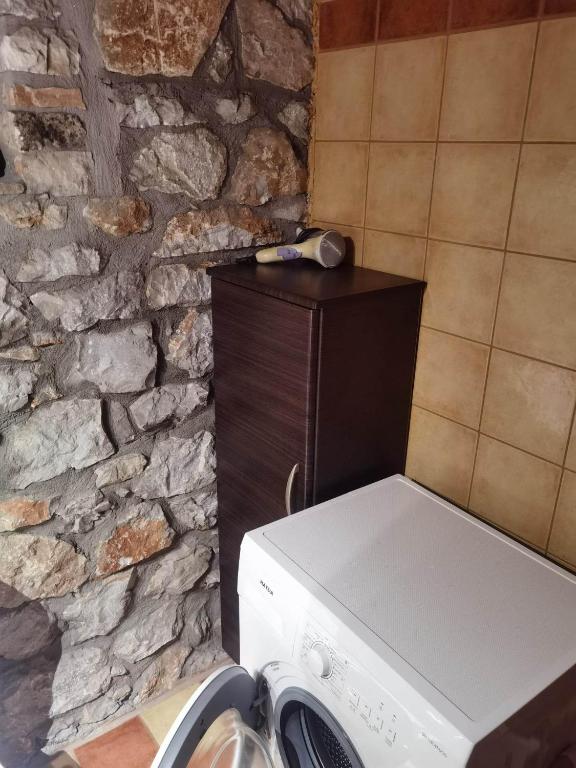 pralka w kuchni z kamienną ścianą w obiekcie Traditional Stone Cottage in Palio Elatohori w mieście Elatochori
