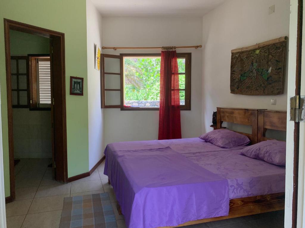 ein Schlafzimmer mit einem Bett mit violetter Bettwäsche und einem Fenster in der Unterkunft Wahnon Guesthouse in Paul