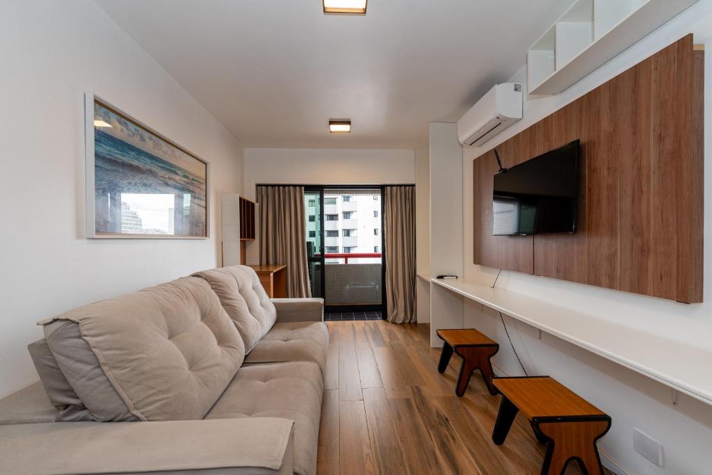 Bristtol Metropolitan Flat في كوريتيبا: غرفة معيشة مع أريكة وتلفزيون بشاشة مسطحة