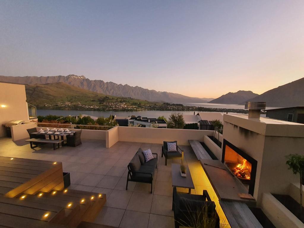 a rooftop patio with a fireplace and a view of the mountains at Luxury Home with Beautiful Lake & Mountain Views in Queenstown