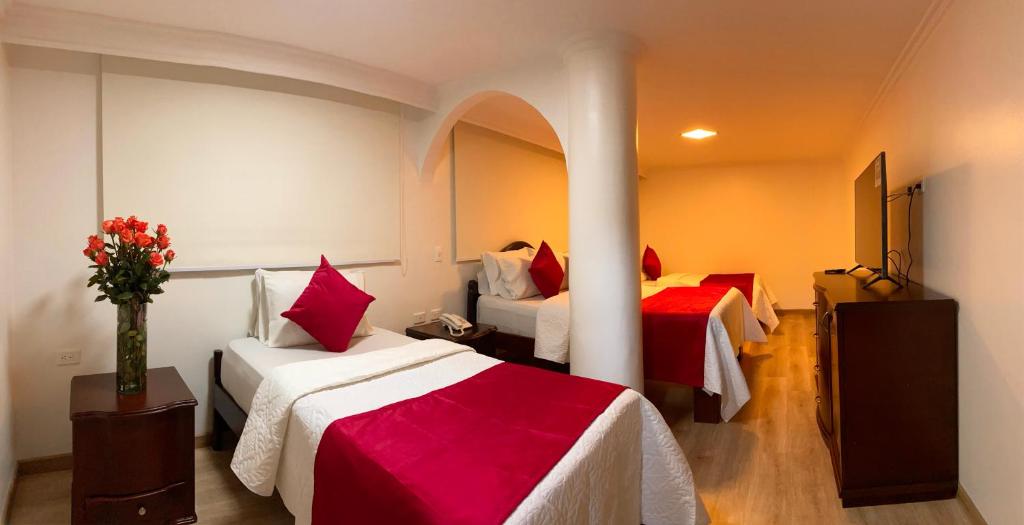 a hotel room with two beds with red and white sheets at Hotel Fontibon in Bogotá