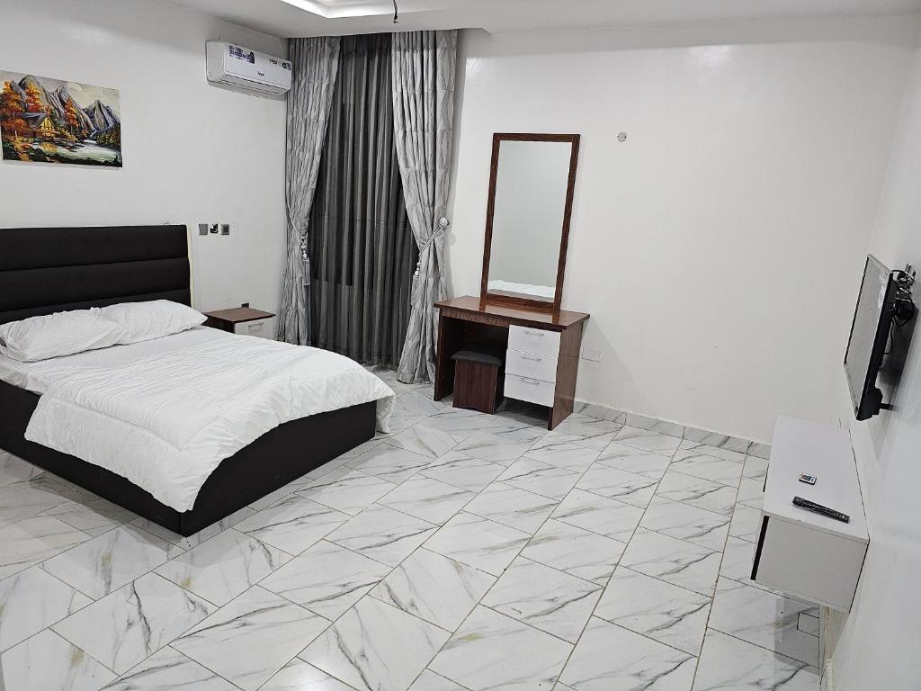 a bedroom with a bed and a mirror on the wall at 5and6 Apartment in Abuja