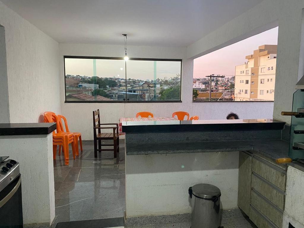 een keuken met oranje stoelen en een tafel en ramen bij NPousadas in Belo Horizonte