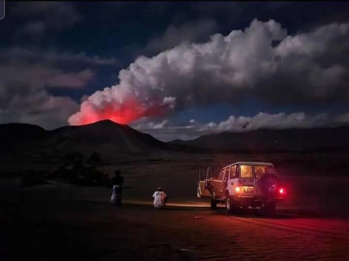 un camion parcheggiato in un campo con un vulcano sullo sfondo di Tanna Lava View Bungalows a Lénakel