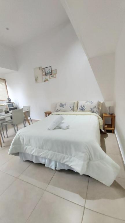 Habitación blanca con cama blanca y piano en Encanto Fueguino calido centrico wifi para dos en Ushuaia
