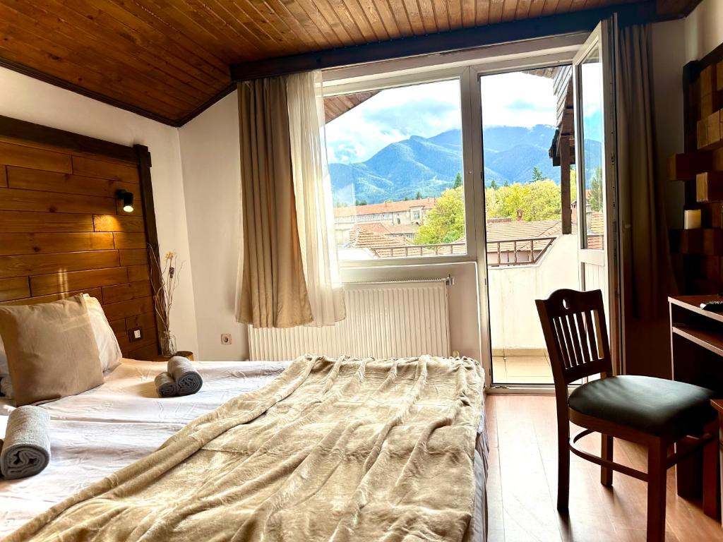 a bedroom with a bed and a large window at Red House Family Hotel in Bansko