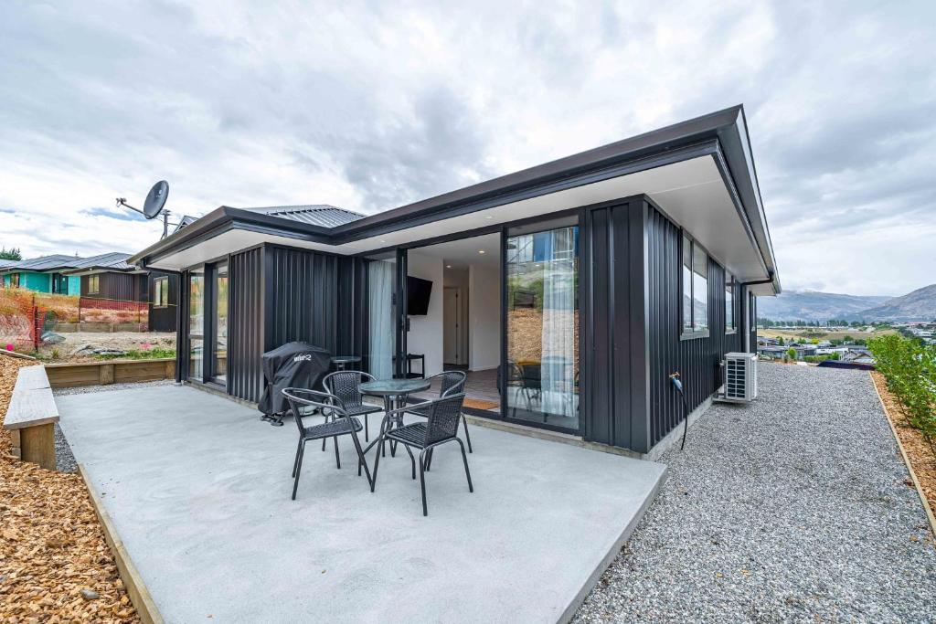 a black house with a table and chairs on a patio at Kirimoko Family Retreat in Wanaka