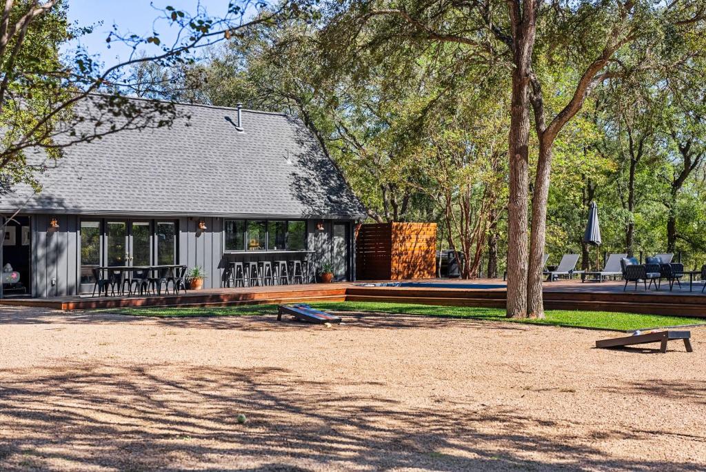 a house in a park with a tree at Hot Tub + Fire Pit + Pool + Game Room ~ Guesthouse in Manor