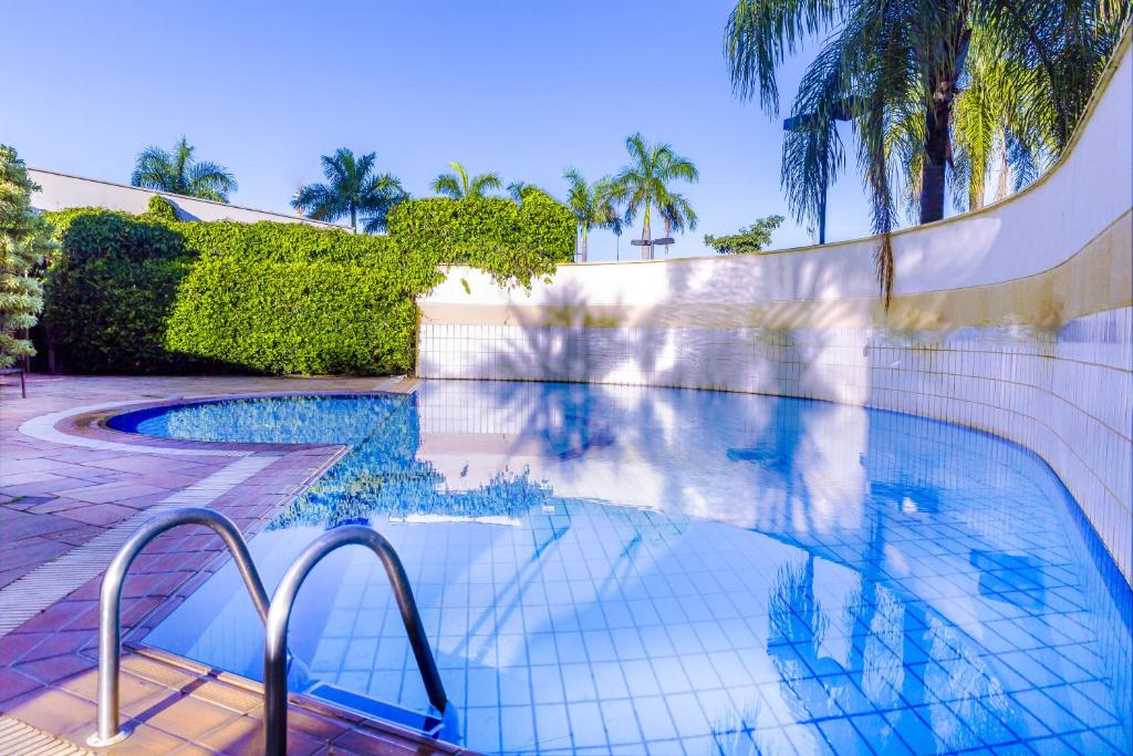 a swimming pool with a fence and palm trees at Comfort Franca in Franca