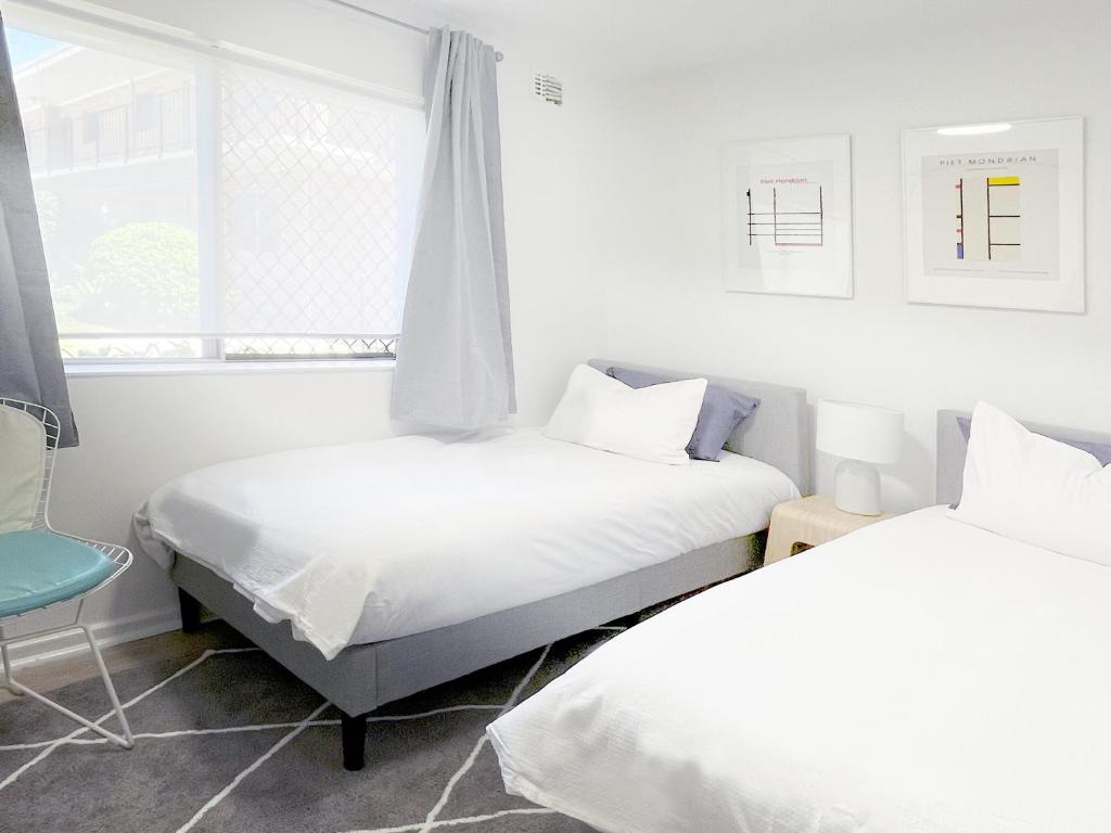 Cette chambre blanche dispose de 2 lits et d'une fenêtre. dans l'établissement Holiday Chic Close to Beach & CBD, à Perth