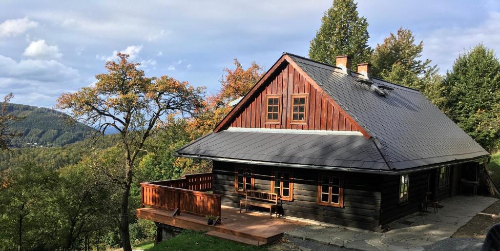 a log cabin with a black roof at Chalupa Řeka - Na samotě u lesa in Řeka