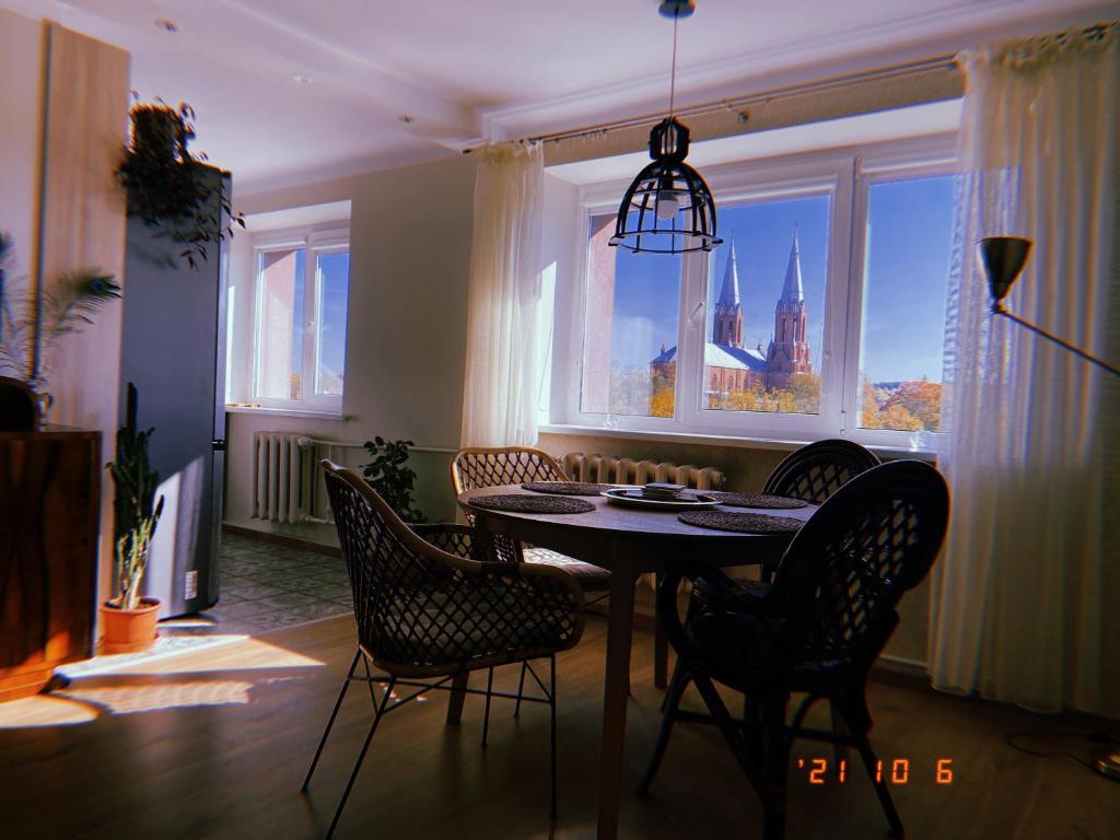 uma sala de jantar com uma mesa e cadeiras e uma janela em Laumžirgių upė - jaukus butas ramiam poilsiui Anykščiuose em Anykščiai