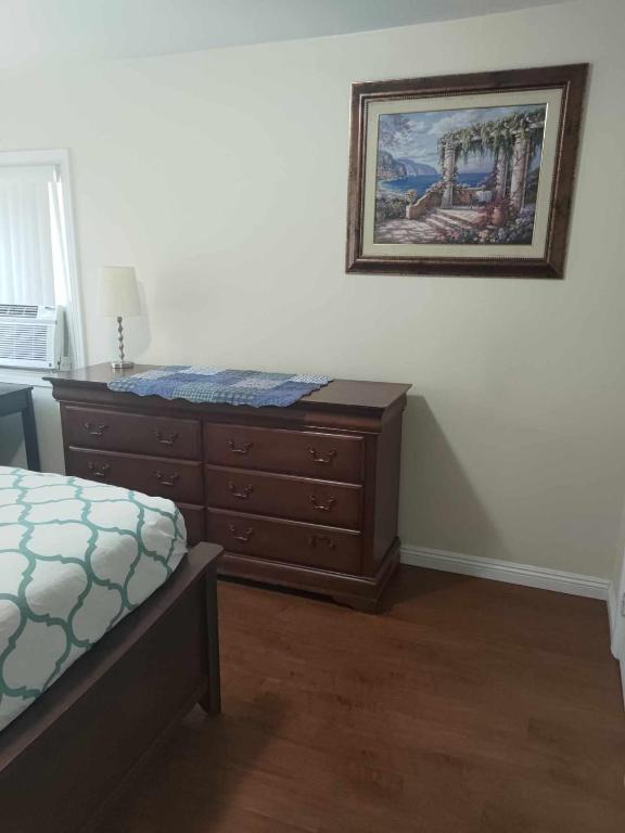 a bedroom with a dresser and a painting on the wall at Secluded Gem in South Gate