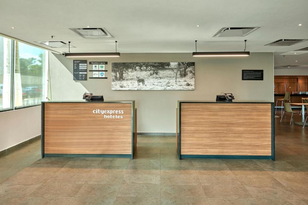 un vestíbulo con dos escritorios de recepción en un edificio en City Express by Marriott Hermosillo, en Hermosillo
