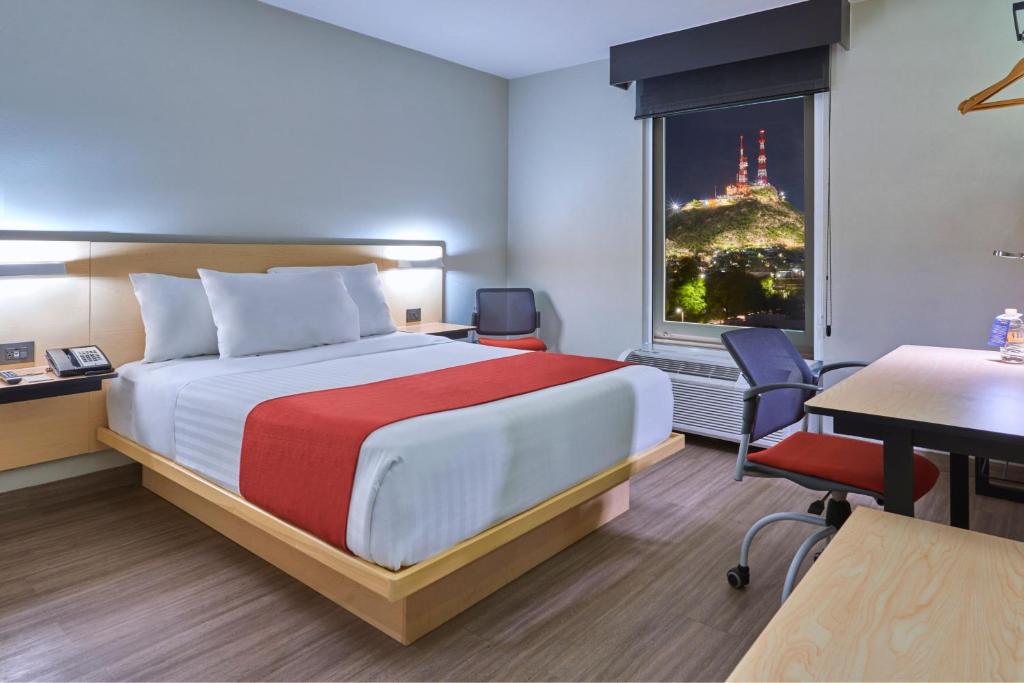 Habitación de hotel con cama, escritorio y ventana en City Express by Marriott Hermosillo, en Hermosillo