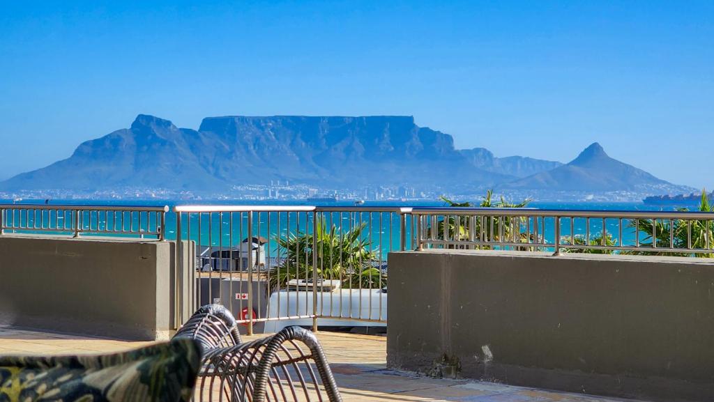 - un balcon avec deux bancs et une vue sur l'océan dans l'établissement Infinity LG8 Beachfront Apartment, à Bloubergstrand