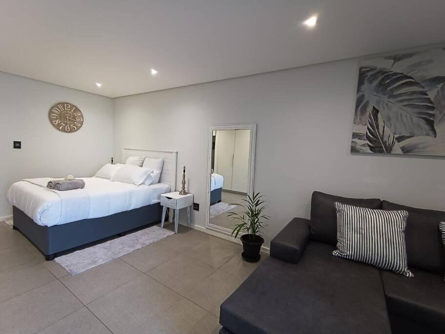 a bedroom with a bed and a living room with a couch at Modern comfy studio apartment with pools in Umhlanga