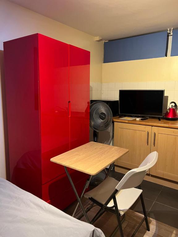 Zimmer mit einem Tisch und einem roten Schrank in der Unterkunft Oxborne Rooms UK - Seaton in London